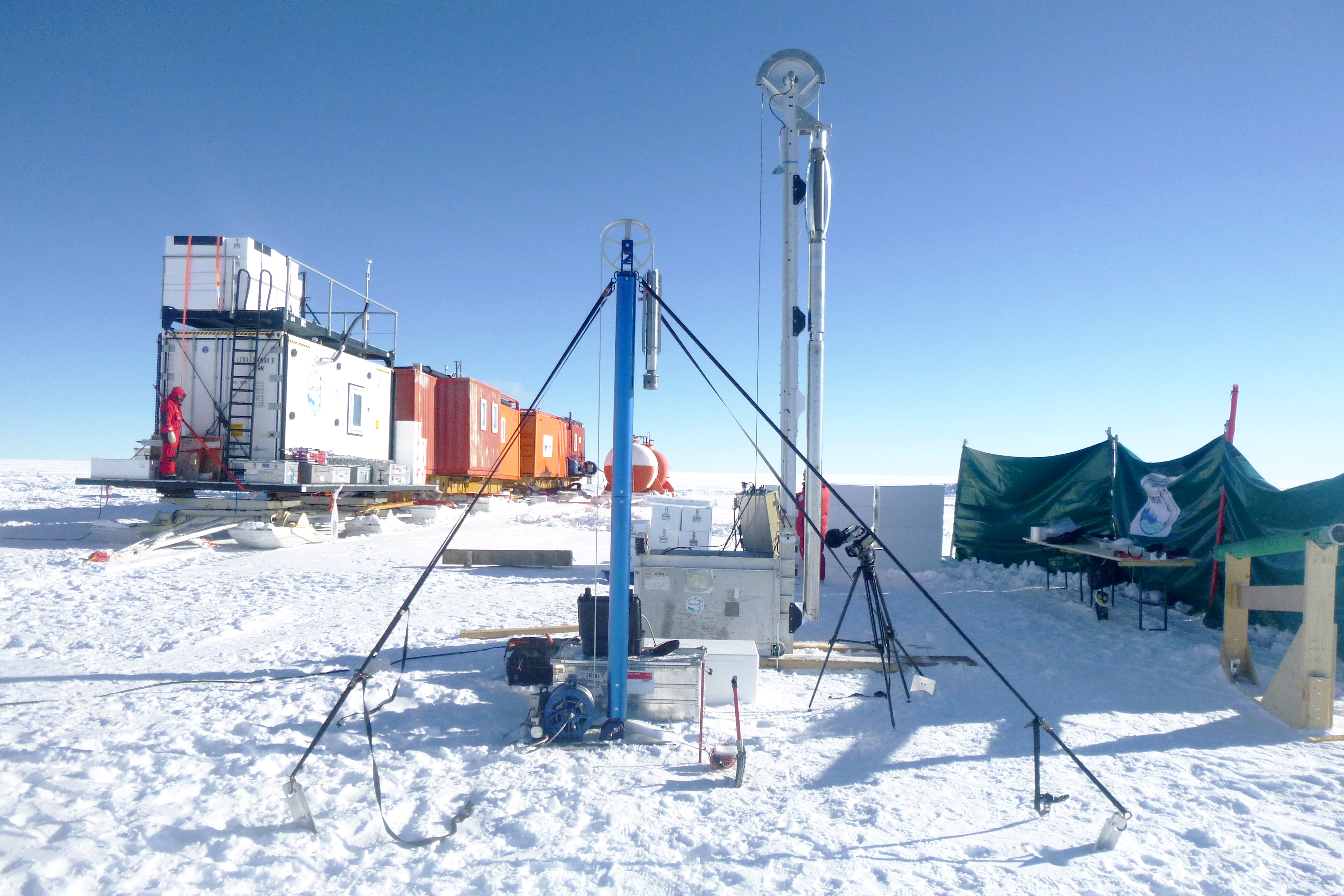 <p>Installation des deux carottiers disponibles sur EAIIST pour forer la glace. Le petit carottier bleu permet de forer jusqu'à 20m, le carottier grand carottier jusqu'à 200m. En arrière fond, le laboratoire chaud (conteneur blanc) et les caravanes vie et énergie. <br class='autobr' />
© A. Vendé, IPEV/PNRA</p>